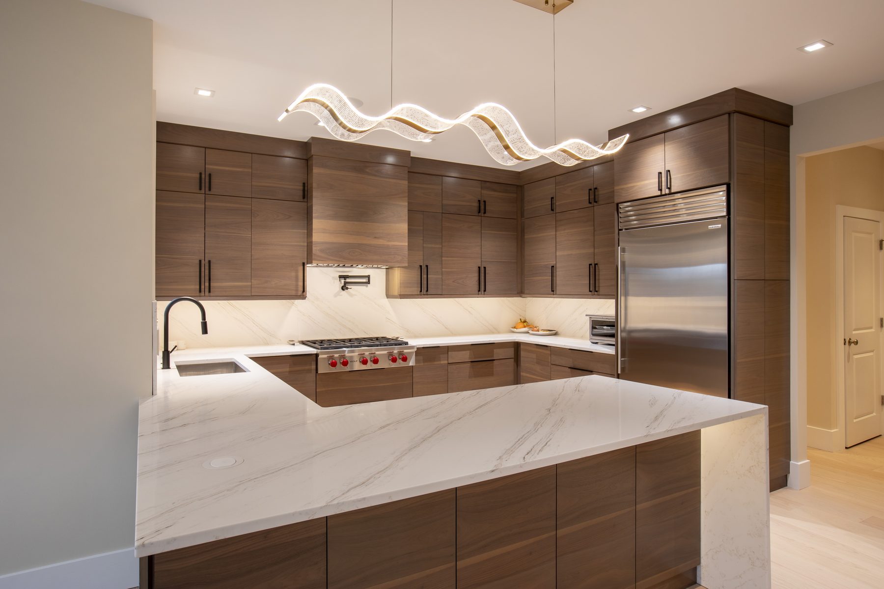 Walnut kitchen with waterfall marble island and sculptural pendant