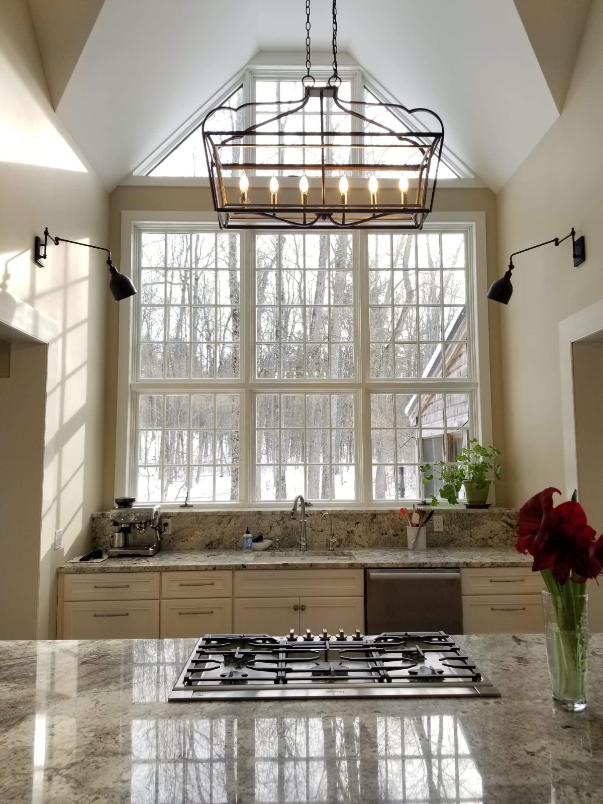 Cathedral-ceiling kitchen with floor-to-ceiling paned windows, lantern chandelier, and granite countertops