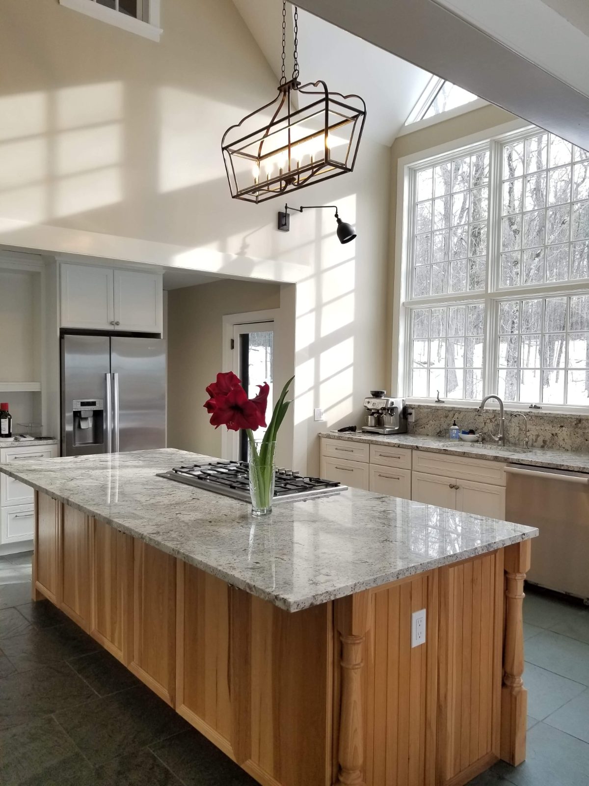 Open kitchen with granite-topped island, cream cabinets, and stainless appliances filled with natural light