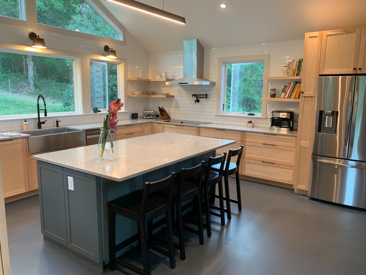 Natural maple cabinetry with slate-green island, quartz counters, and white subway tile backsplash